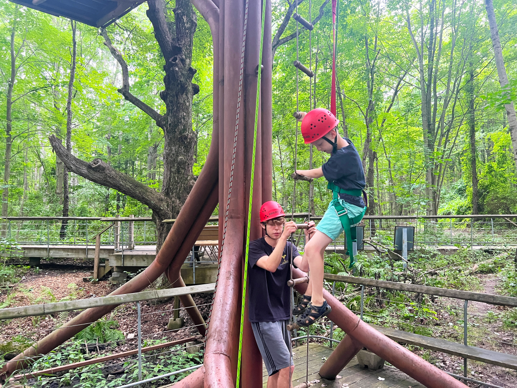 boy climbing the ropes course at summer camp