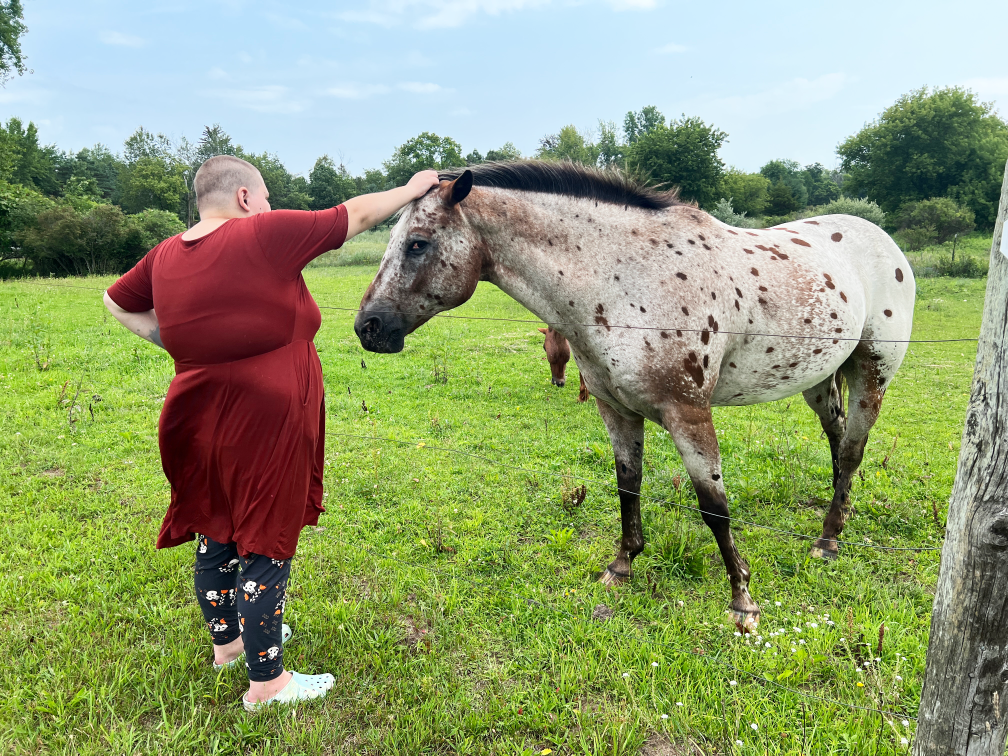 A girl pets a horse at our weekend respite camp at the Fowler Center