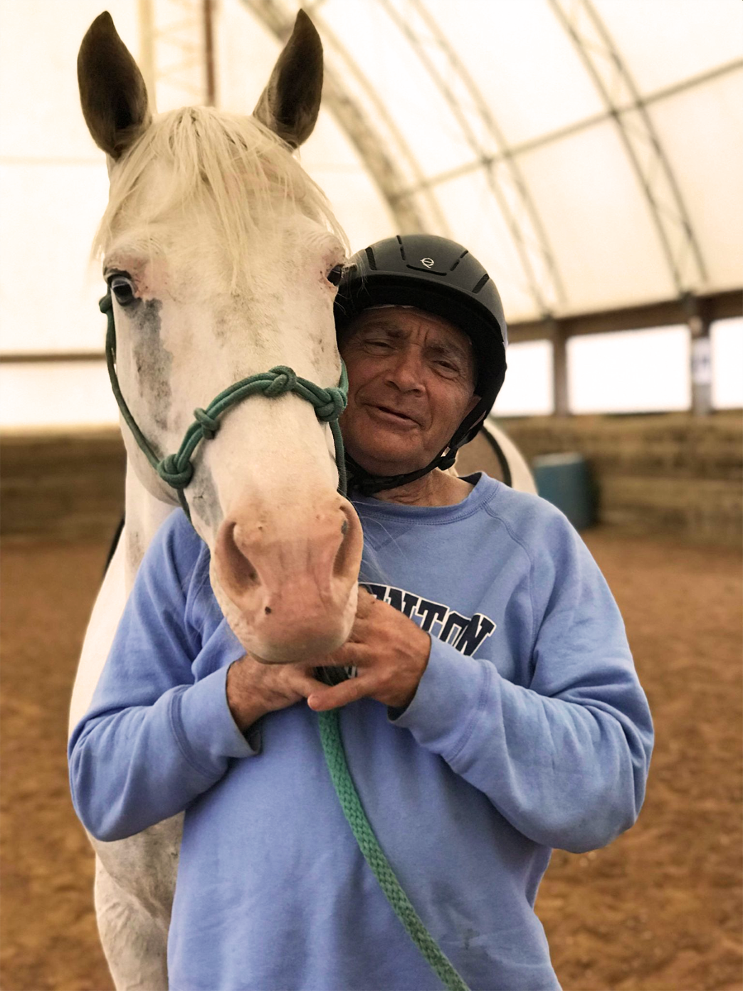 A man stands with a horse in the riding stable. Our equestrian programs are a great way to have fun and build self-confidence.