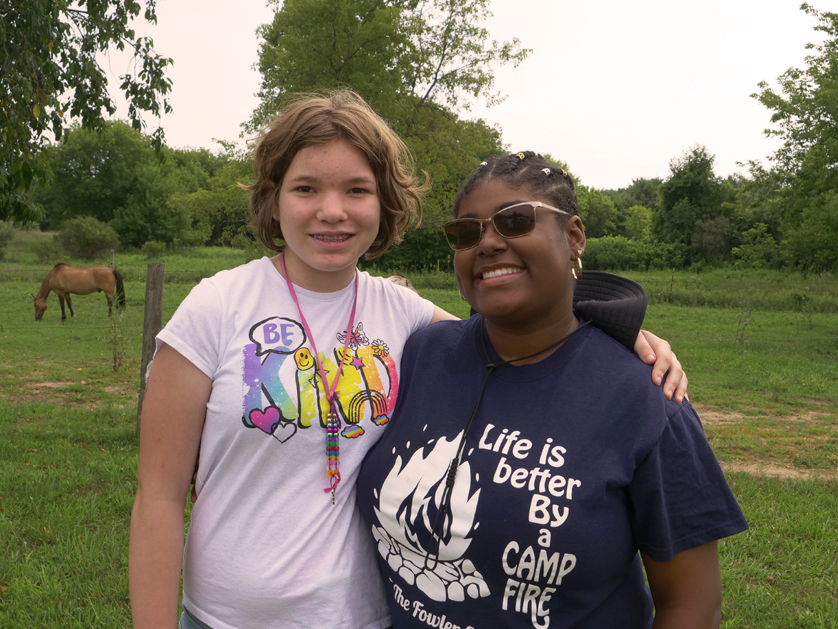 A camper and counsellor pause to smile at the equestrian center