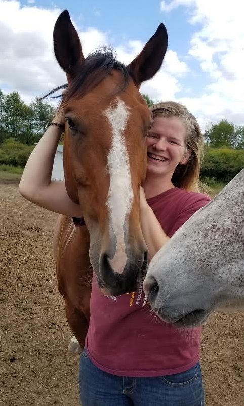 A man stands with a horse in the riding stable. Our equestrian programs are a great way to have fun and build self-confidence.